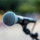 A microphone on a stand captured outdoors with a blurred background.