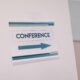 Close-up of a conference directional sign indoors, guiding participants.