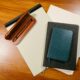 An overhead view of office supplies including a pen, notebook, and folder on a wooden desk.